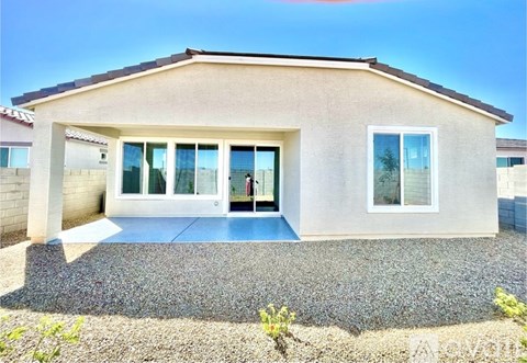 A small house with a gravel driveway in front.