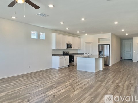 A spacious kitchen with white cabinets and a wooden floor.