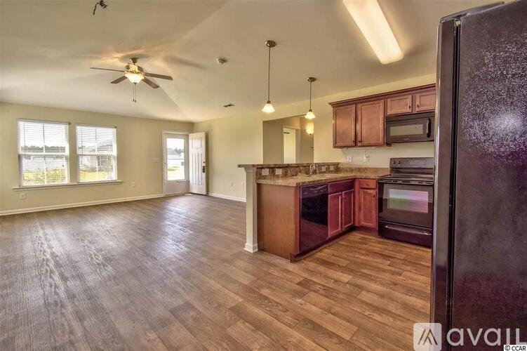 A kitchen with wooden floors and a ceiling fan.