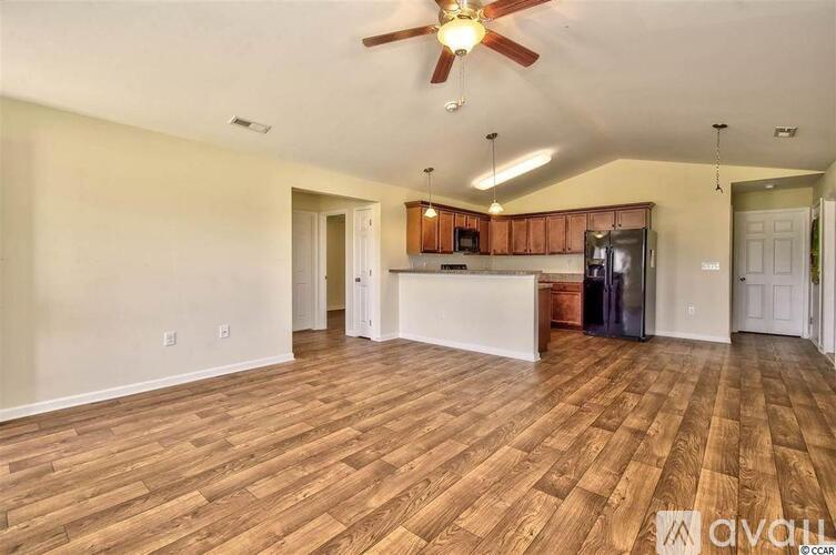 A spacious room with wooden flooring and a ceiling fan.