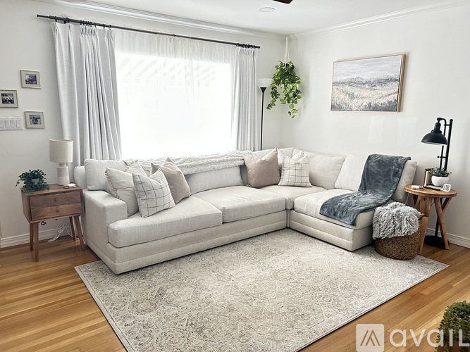 A living room with a large sectional sofa and a rug in the center.