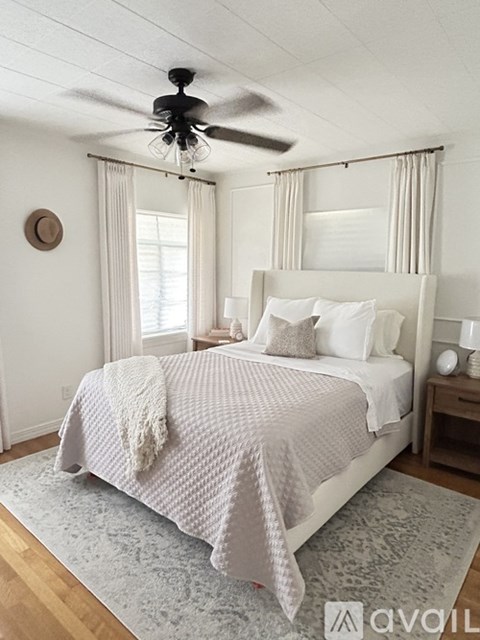 A bedroom with a bed, a ceiling fan, and a rug.