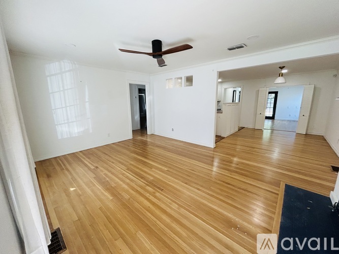 A spacious room with wooden flooring and a ceiling fan.