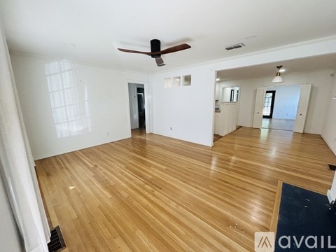 A spacious room with wooden flooring and a ceiling fan.