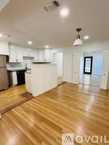 A kitchen with white cabinets and a wooden floor.