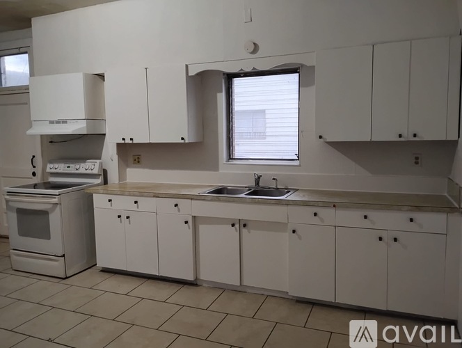 A kitchen with white cabinets and a tiled floor.