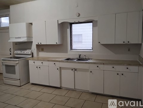 A kitchen with white cabinets and a tiled floor.