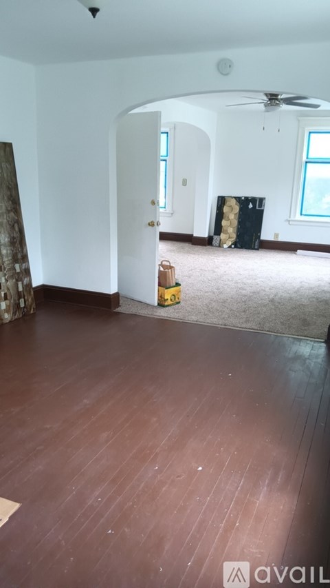 A room with wooden flooring and a fan in the corner.