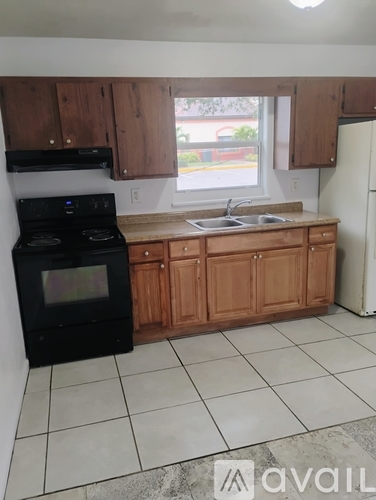 A kitchen with a black stove top oven, wooden cabinets, and a white refrigerator.