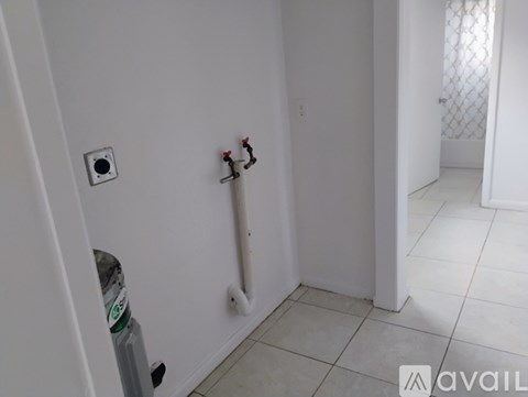 A white bathroom with a toilet paper holder and a bottle of water on the floor.