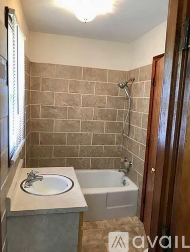 A bathroom with a tiled shower area and a white sink.
