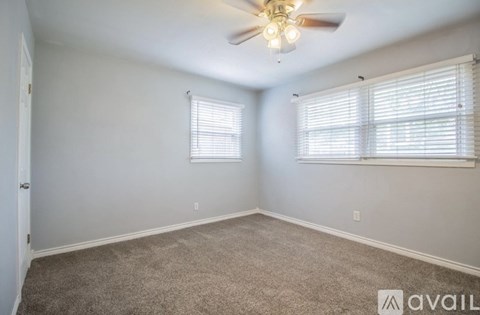 A room with a ceiling fan and two windows with blinds.