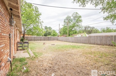 A backyard with a wooden fence and a small tree.