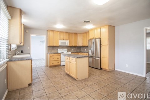A kitchen with wooden cabinets and tile flooring.