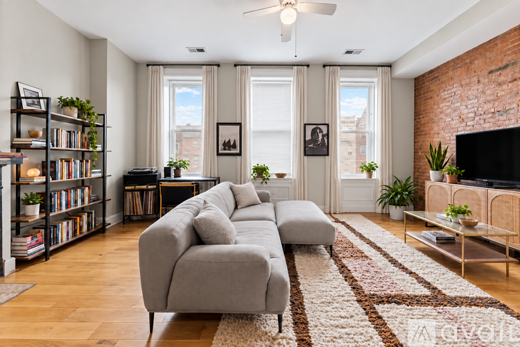 A living room with a grey couch, a bookshelf, a rug, and a television.