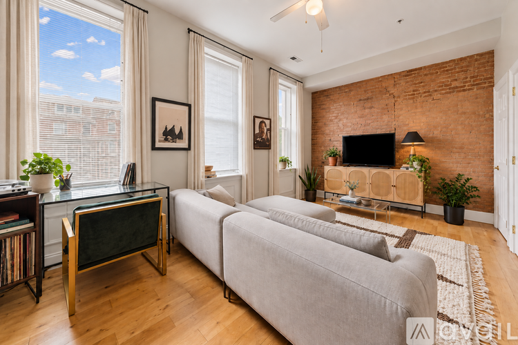 A living room with a grey sofa, a blackboard and a brick wall.