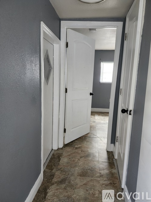 A hallway with a white door and a grey wall.