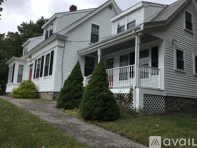 A two-story house with a white porch and a red door.