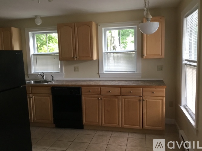 A kitchen with wooden cabinets and a black fridge.