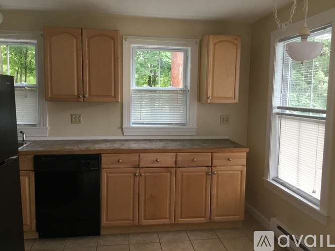 A kitchen with wooden cabinets and a black dishwasher.