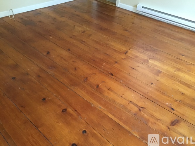 A room with wooden flooring and a white wall.