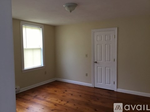 A room with a white door and wooden flooring.