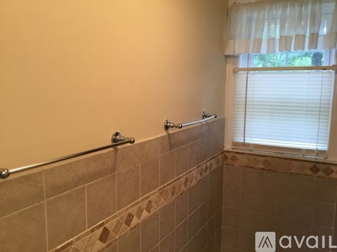 A bathroom with a tiled shower and a window with blinds.