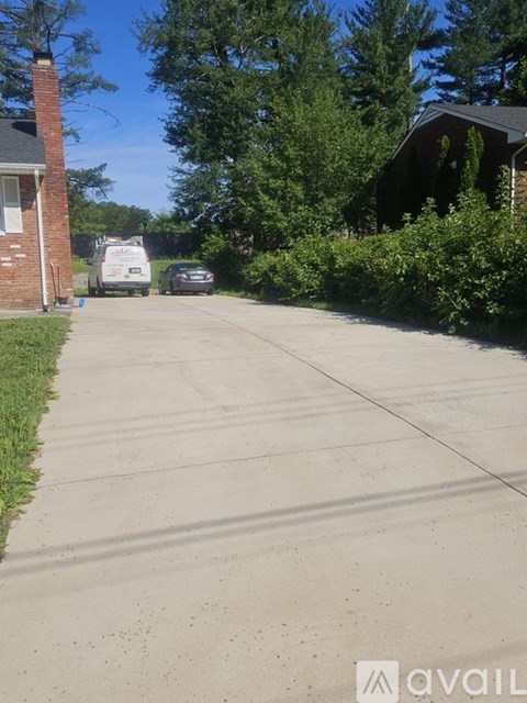 A residential street with a parked car and a house with a chimney.