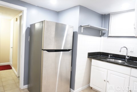 A stainless steel refrigerator in a kitchen with white cabinets.