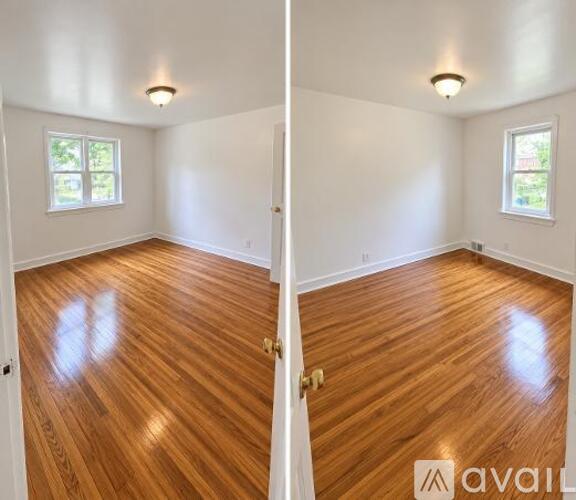 A room with wooden floors and two windows.