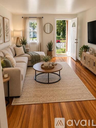 A living room with a grey couch, a coffee table, and a flat screen TV mounted on the wall.