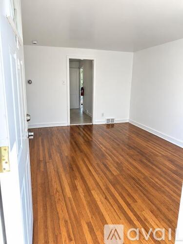 A room with wooden flooring and white walls.