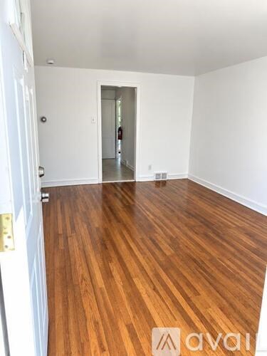A room with wooden flooring and white walls.