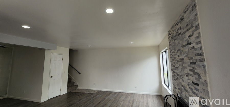 A spacious room with a stone wall and wooden flooring.