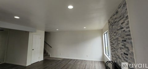 A spacious room with a stone wall and wooden flooring.