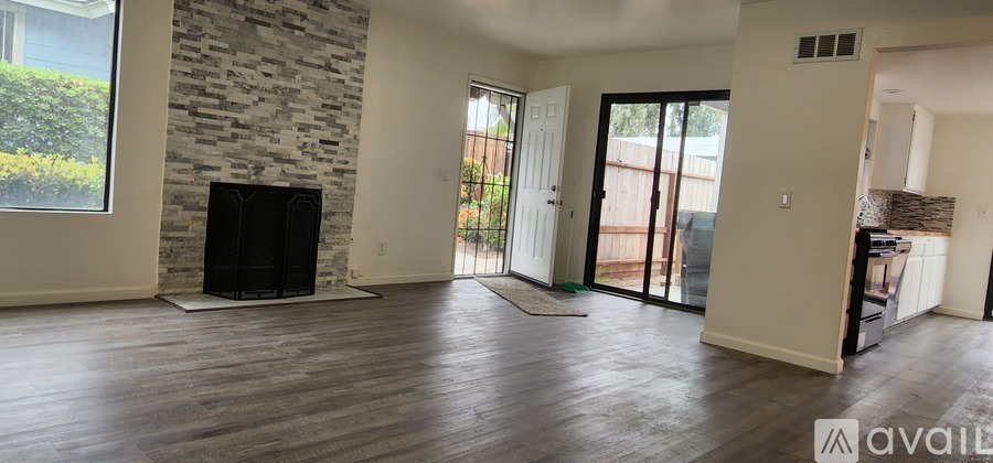 A living room with a stone fireplace and wooden floors.