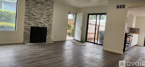 A living room with a stone fireplace and wooden floors.