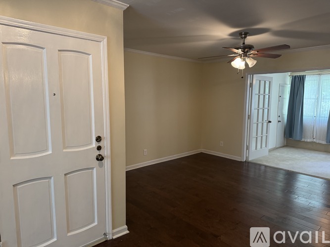 A room with a white door and a ceiling fan.