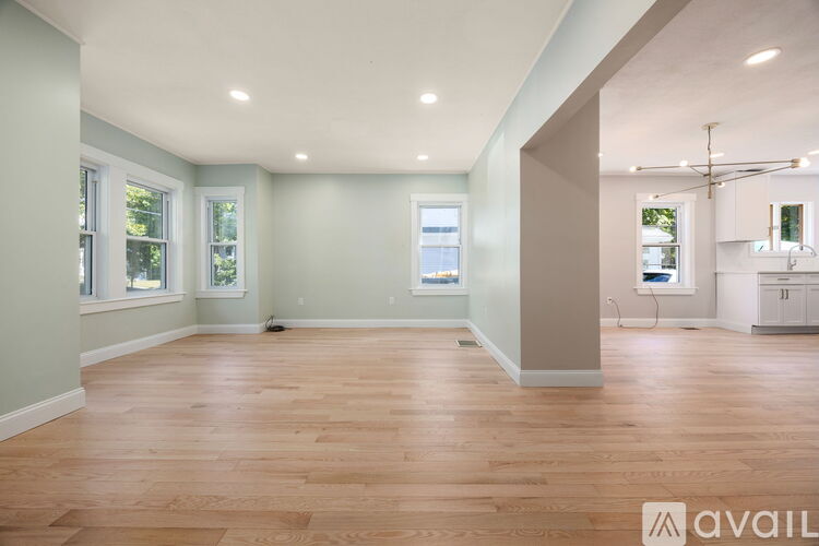 A spacious room with wooden flooring and a large window.