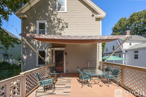 A patio with a table and chairs is covered by a white awning.