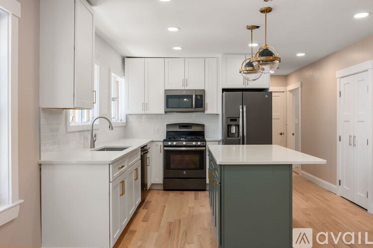 A kitchen with white cabinets and a dark island.