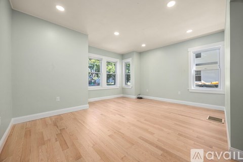 A room with wooden flooring and a window showing a view of trees.