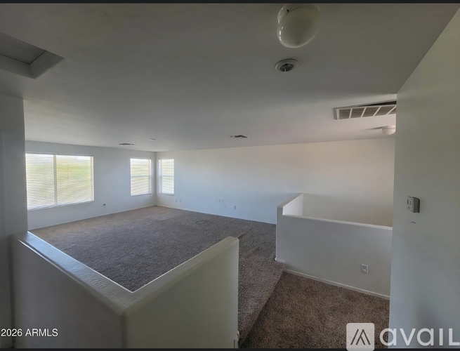 A room with a carpeted floor and a window with blinds.