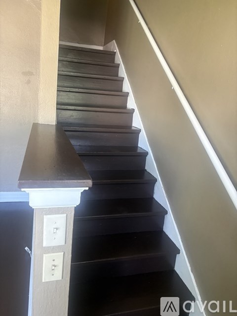 A staircase with a grey tread and a white riser with three switches on it.