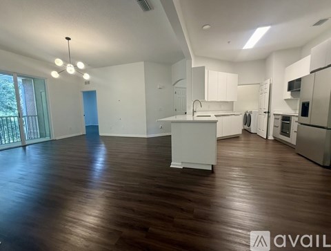 A spacious kitchen and living room with wooden floors and white walls.