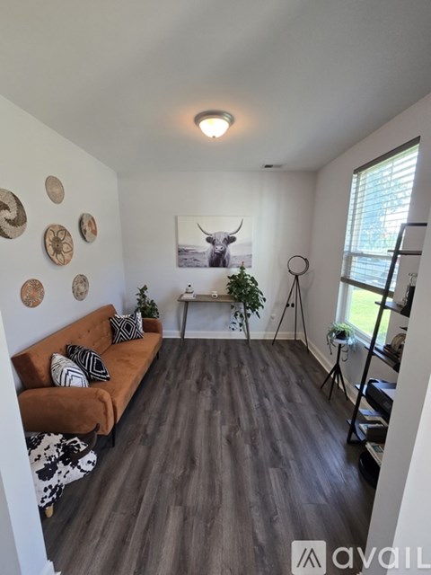A living room with a brown couch and a cow print rug.