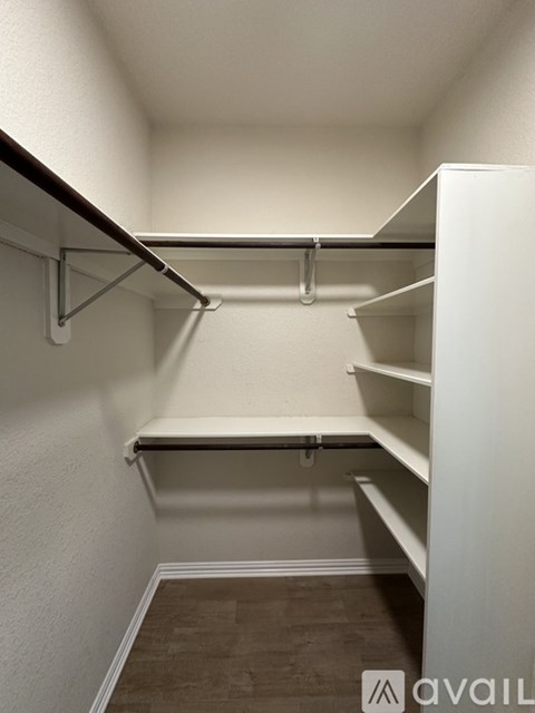 A white closet with shelves and a pipe on the wall.