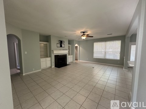 A spacious living room with a fireplace and a ceiling fan.