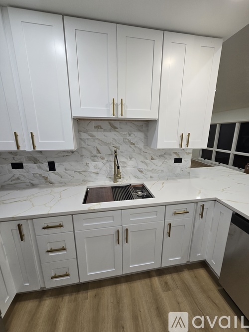 A kitchen with white cabinets and a marble backsplash.