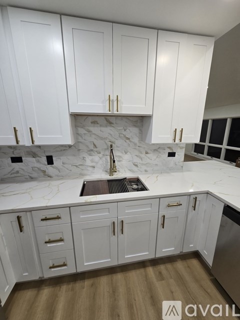 A kitchen with white cabinets and a marble backsplash.